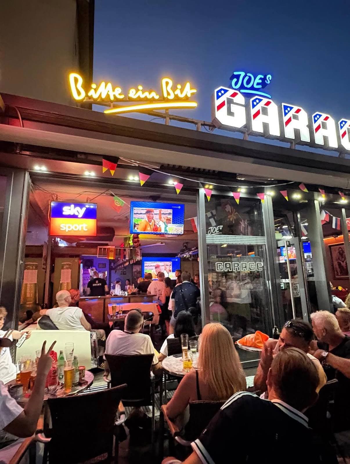 Beleuchteter Eingang von Joe’s Garage bei Nacht