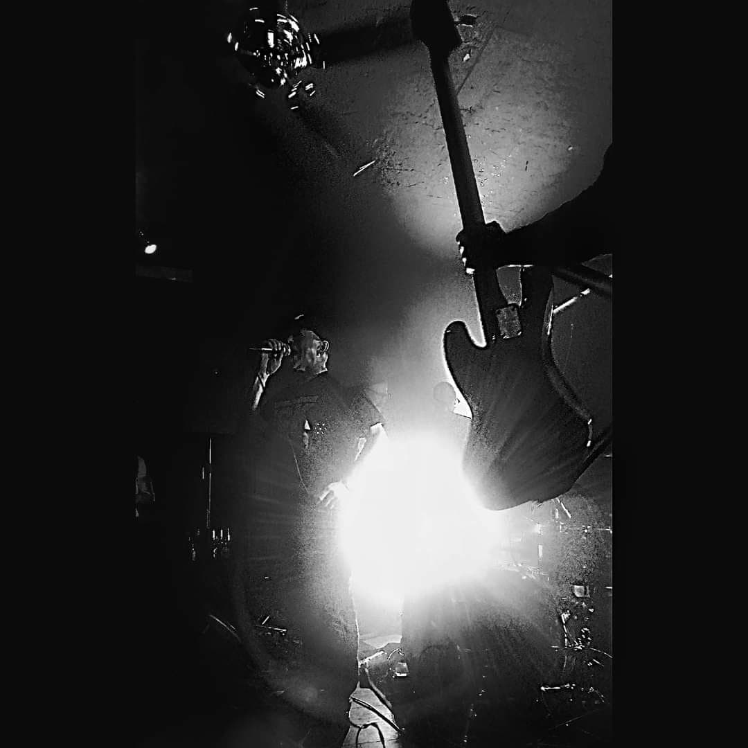 Schwarz-Weiß-Aufnahme eines Sängers und einer Gitarre im Gegenlicht