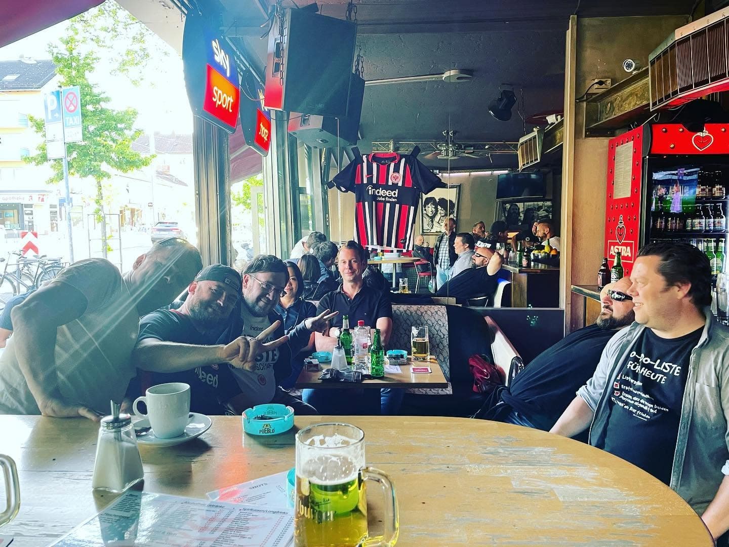 Gäste sitzen gemeinsam an Tischen im hellen Barbereich